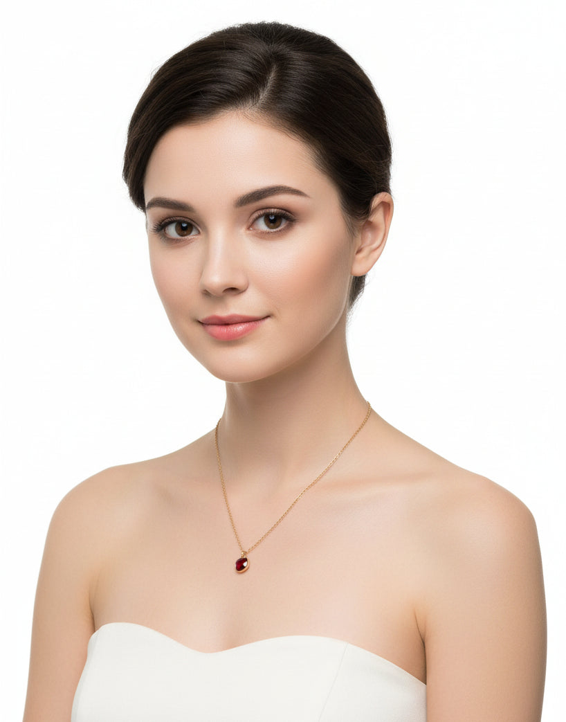 A woman wiht gold chain necklace with red crystall on a white backround background