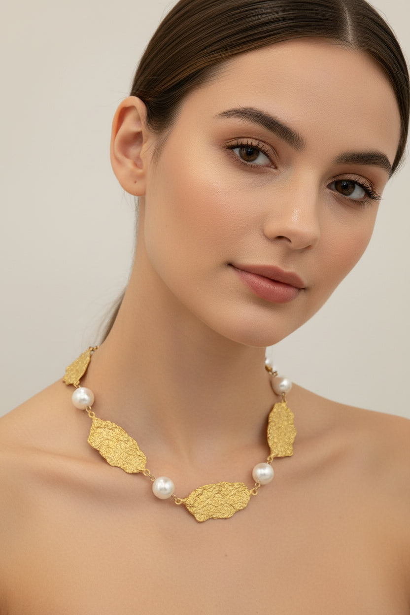 Gold leaf and pearl necklace on a woman' s neck