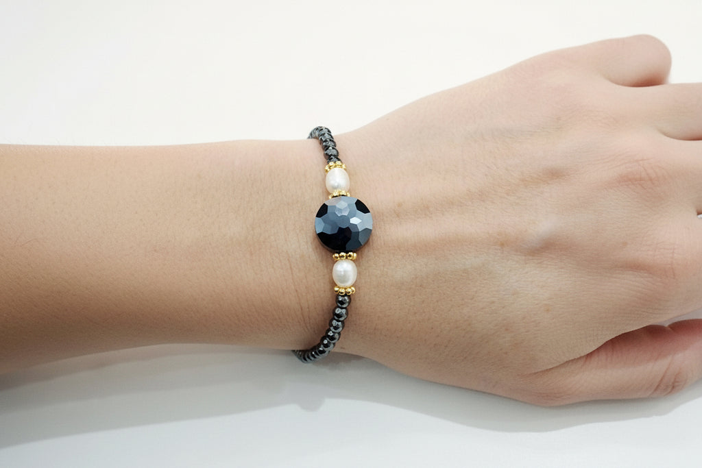 Bracelet with black beads and a large central stone on a wrist against a white background