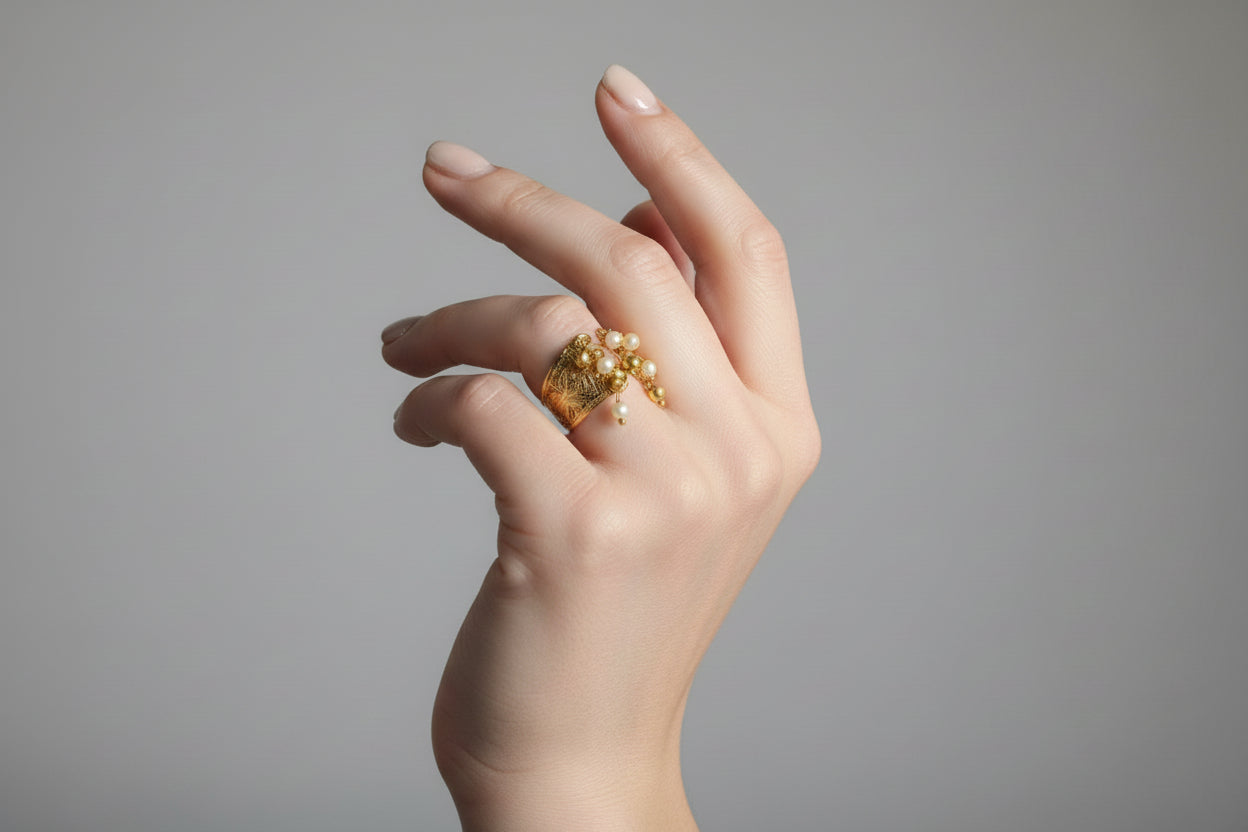 Close-up of a hand wearing a gold ring with gemstones.