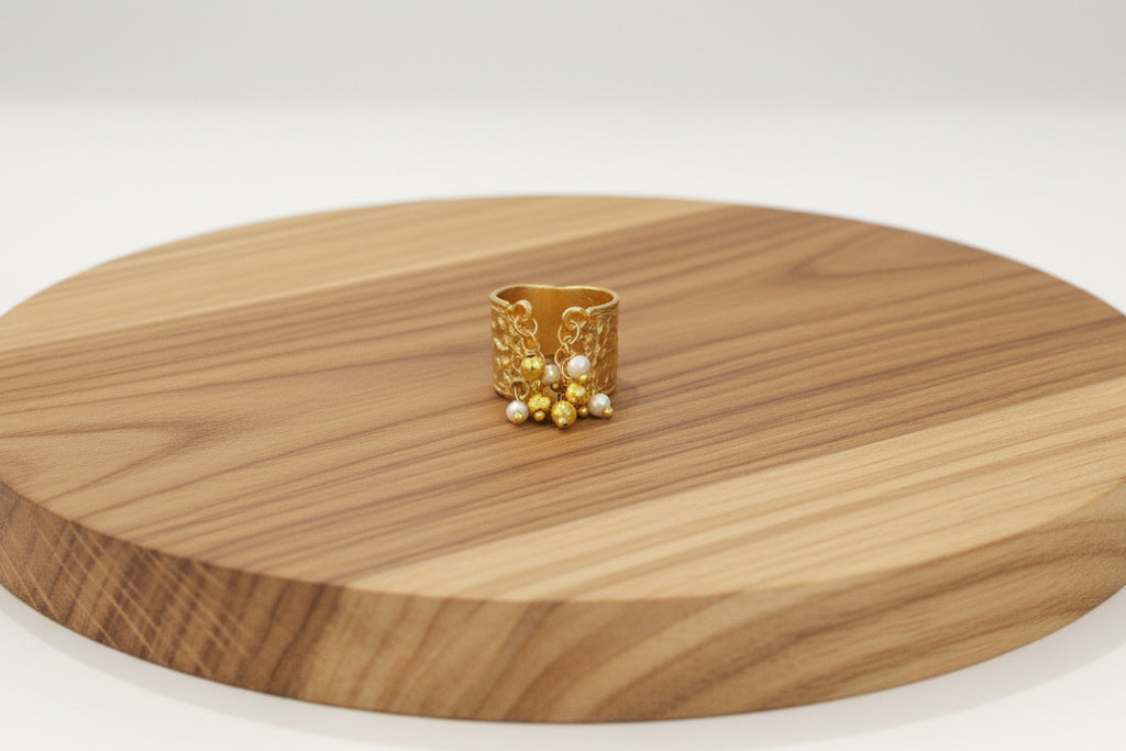 Gold ring with small beads on a wooden surface