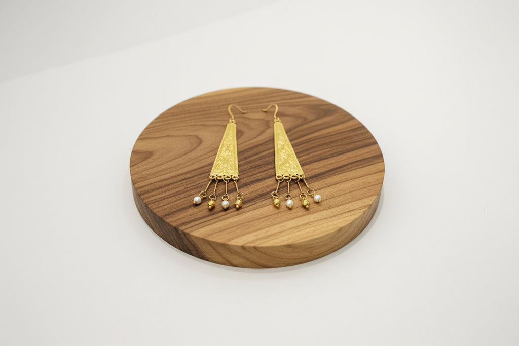 Gold earrings on a wood surface