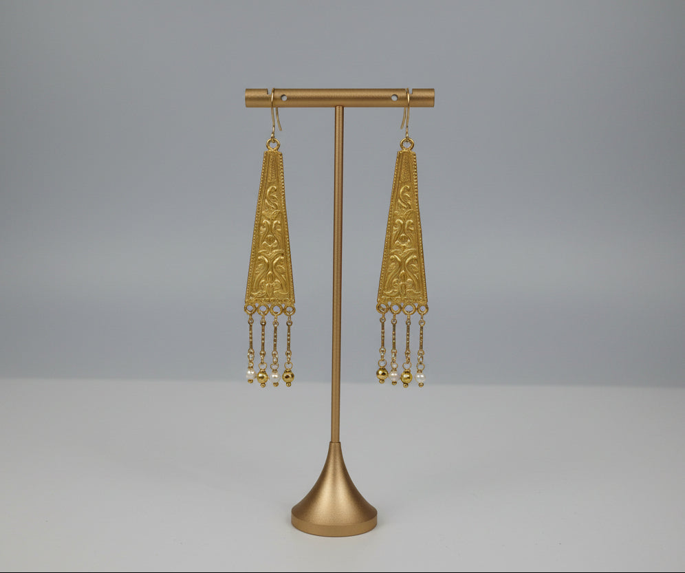 Gold earrings on a gold stand with a white background