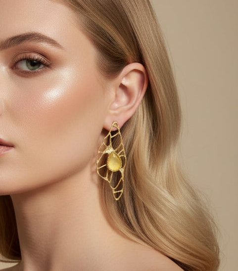 Woman wearing gold jewelry including earrings and a ring on a beige background