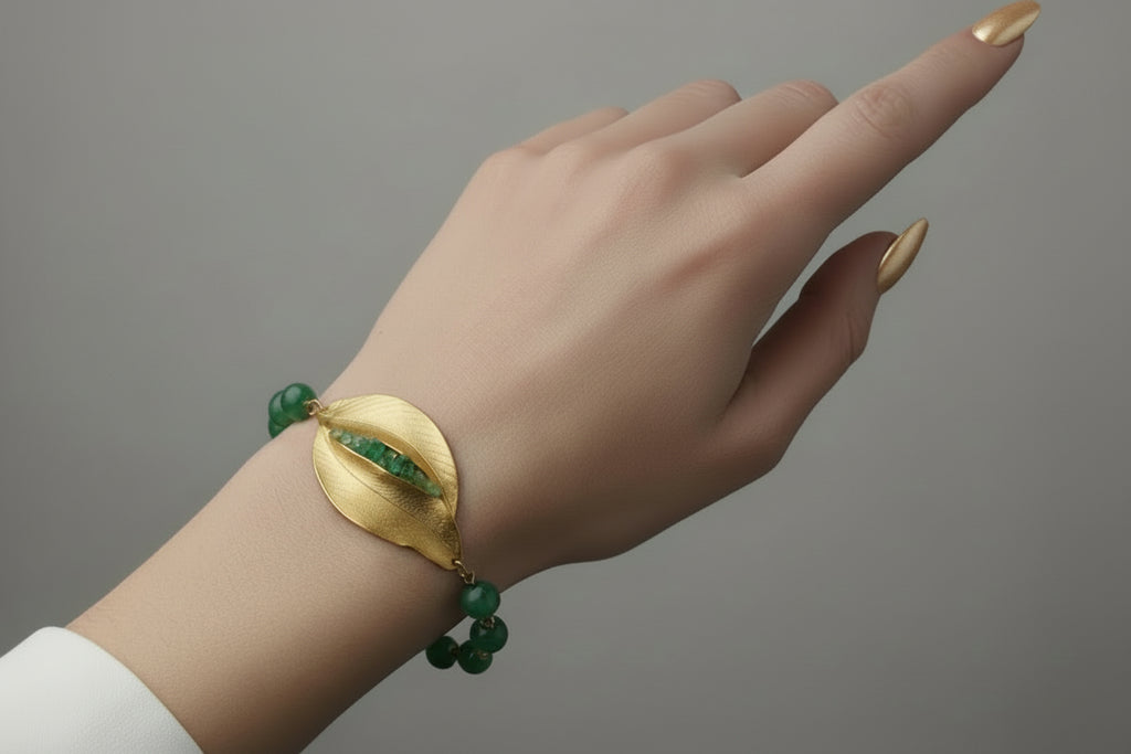 Hand wearing a green and gold bracelet on a studio background