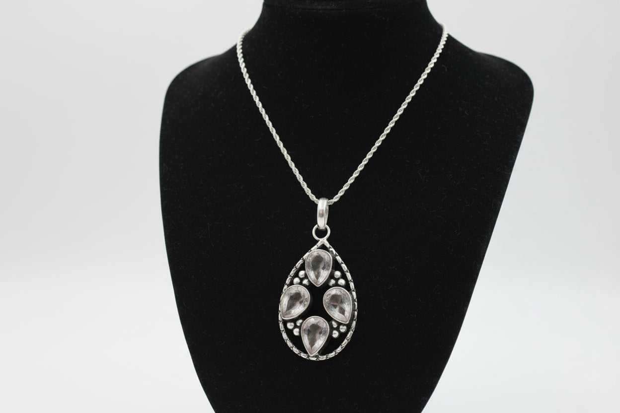 Silver pendant necklace with crystalls on a black stand