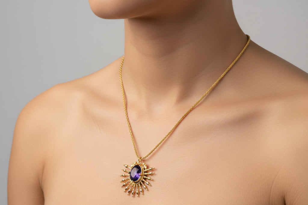 γυναίκα φοράει ένα κολιέ με χρυσή λεπτή αλυσίδα και ακτινωτό κρεμαστό στοιχείο με μεγάλη φυσική μωβ πέτρα στο κέντρο.